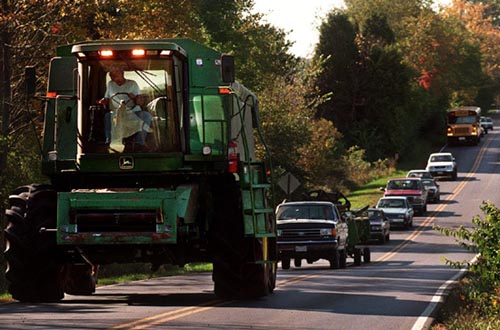 A tractor backs up traffic on a paved road.
